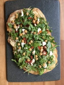 Grilled Thin Crust Pizza with Hummus, Arugula, Sun-dried Tomato, Goat Cheese and Chickpeas